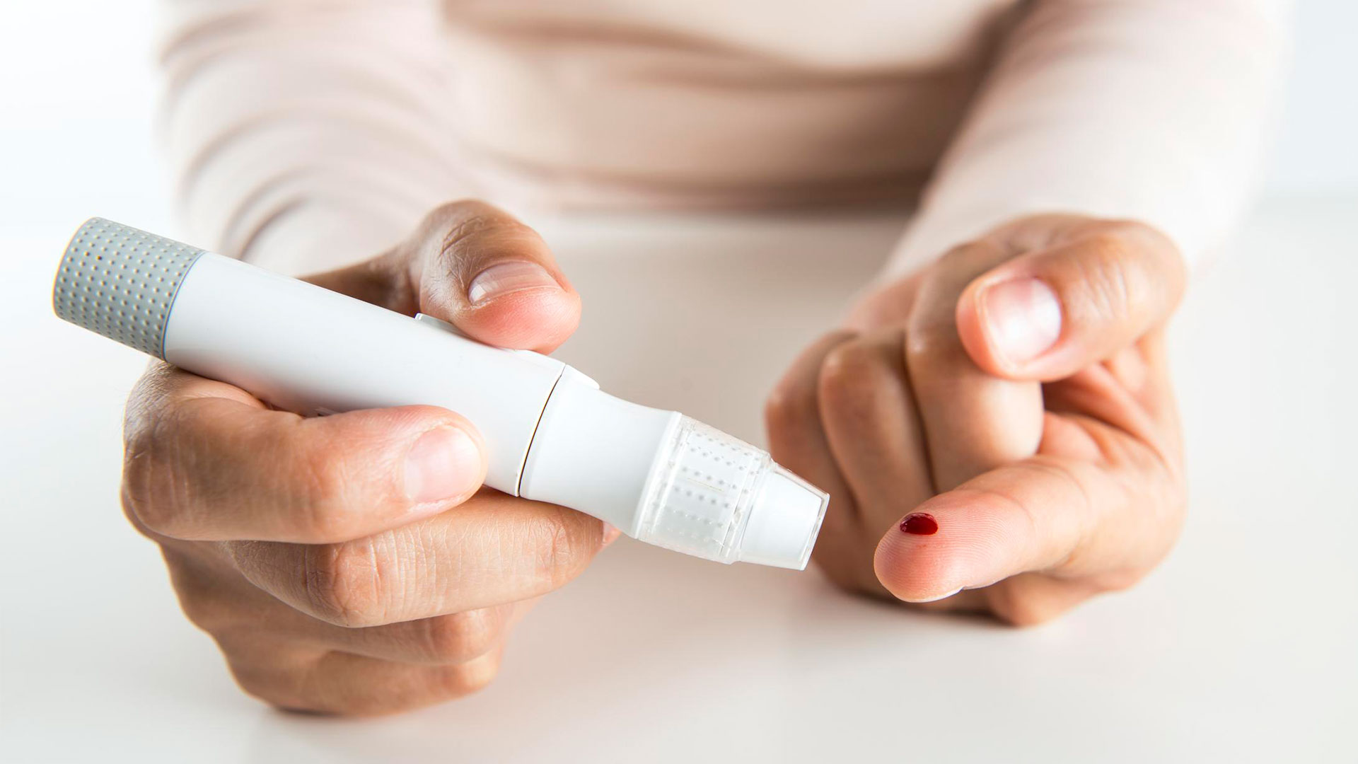 Persona realizando una punción en el dedo con una lanceta para medir la glucosa en sangre